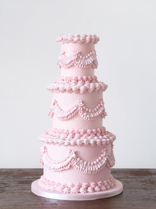 Bridgerton inspired Lambeth wedding cake by Saddleworth based Union Cakes. An alternative and budget savvy wedding cake in pale pink adorned with swags, ruffles, shells, and pearls.