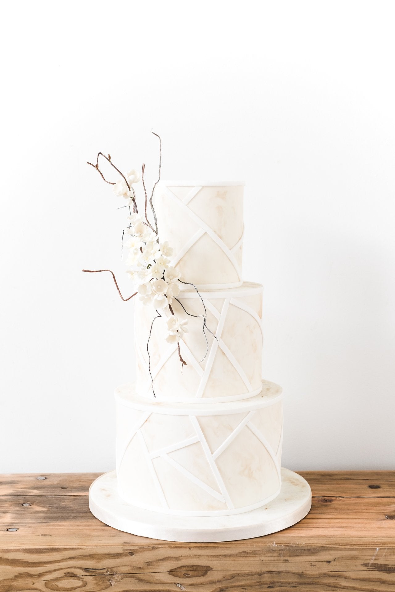 Modern wedding cake with a coastal, sun-bleached design and delicate sugar flowers from Saddleworth based Union Cakes
