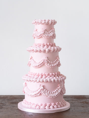 Lambeth wedding cake by Saddleworth based Union Cakes. It's a playful blend of Victorian England, '80s kitsch, and a dash of French neoclassical flair, adorned with swags, ruffles, shells, and pearls.