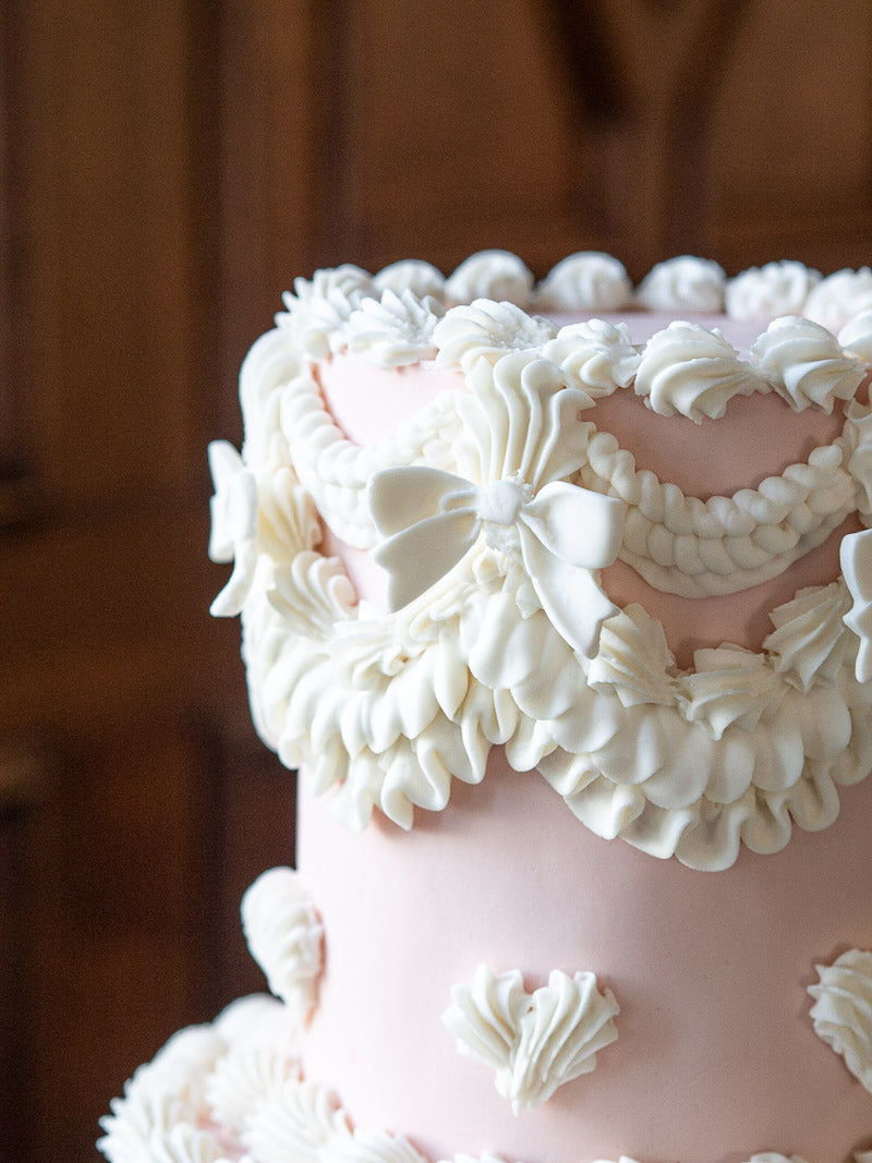 Pretty royal iced detail on the top of a peachy-pink wedding cake