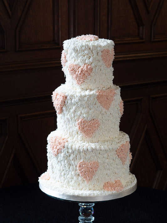Fun shaggy wedding cake with peach hearts photographed at The Saddleworth Hotel in Greater Manchester