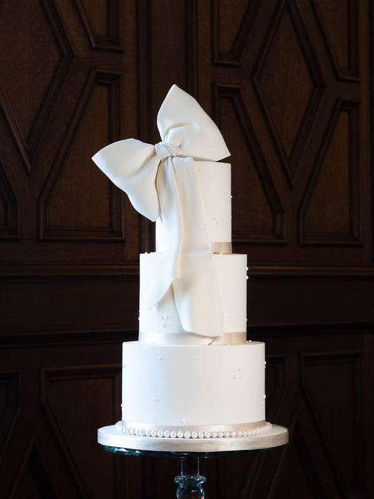 Fashionable ivory wedding cake with an elegant sugarpaste bow pictured at The Saddleworth Hotel in Greater Manchester