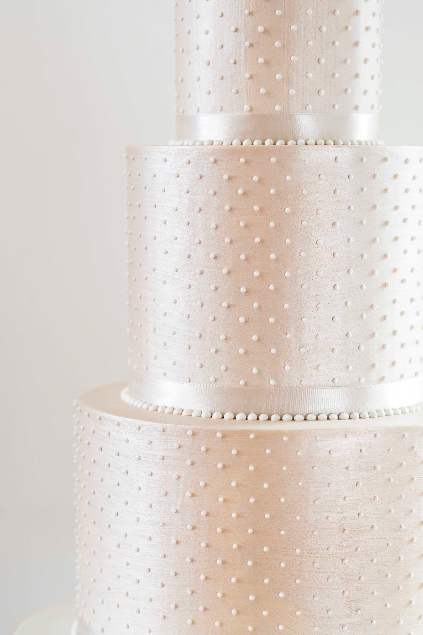 Champagne coloured, budget friendly deep tiered modern wedding cake in a simple classic design with sharp edges and piped pearls