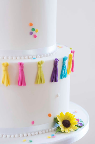 Brightly coloured sugar tassles contrast with pristine white icing on a great value wedding cake.