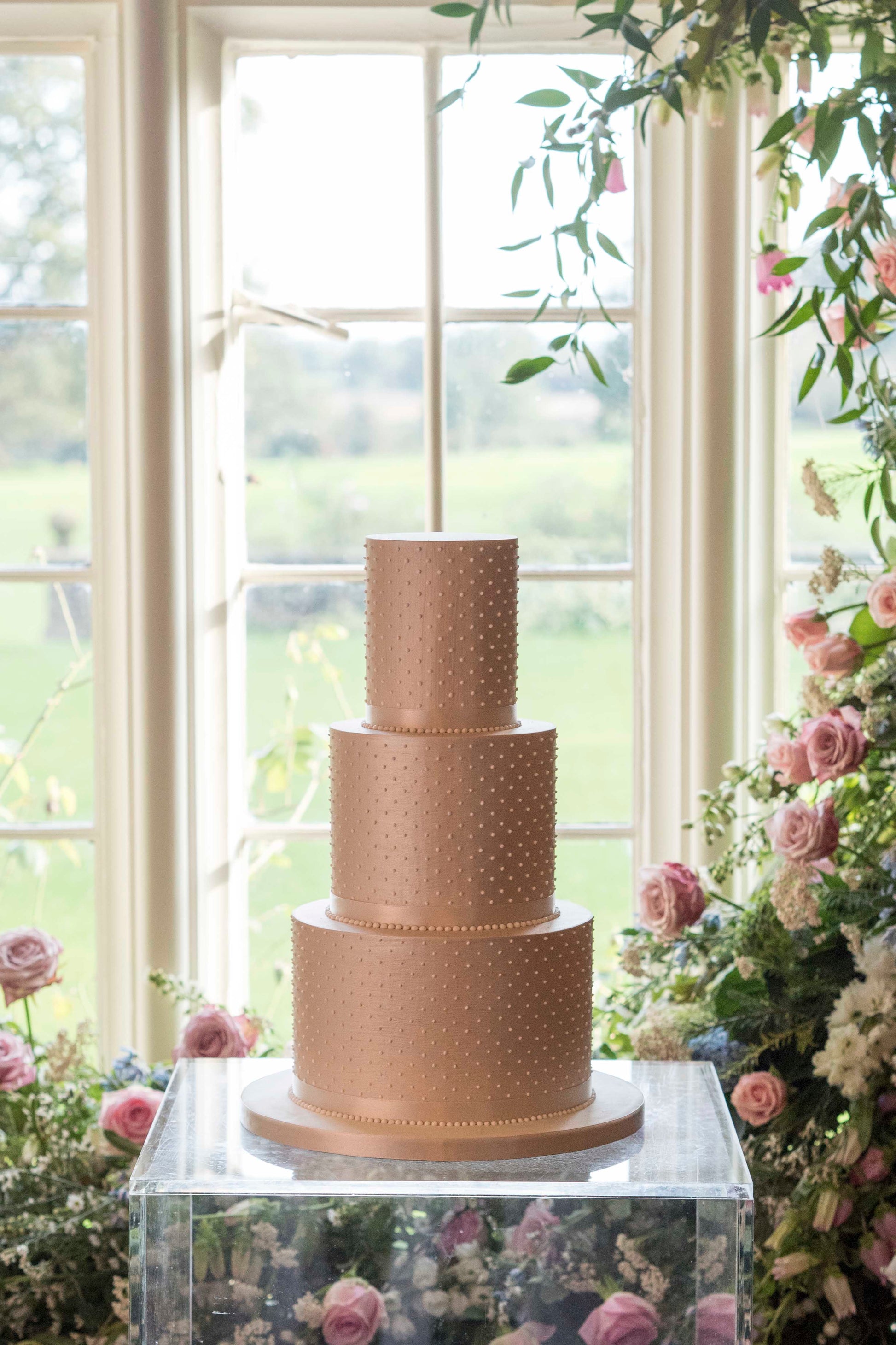 Simple and understated deep tiered modern wedding cake with sharp edges in a luxurious champagne colour with piped pearls
