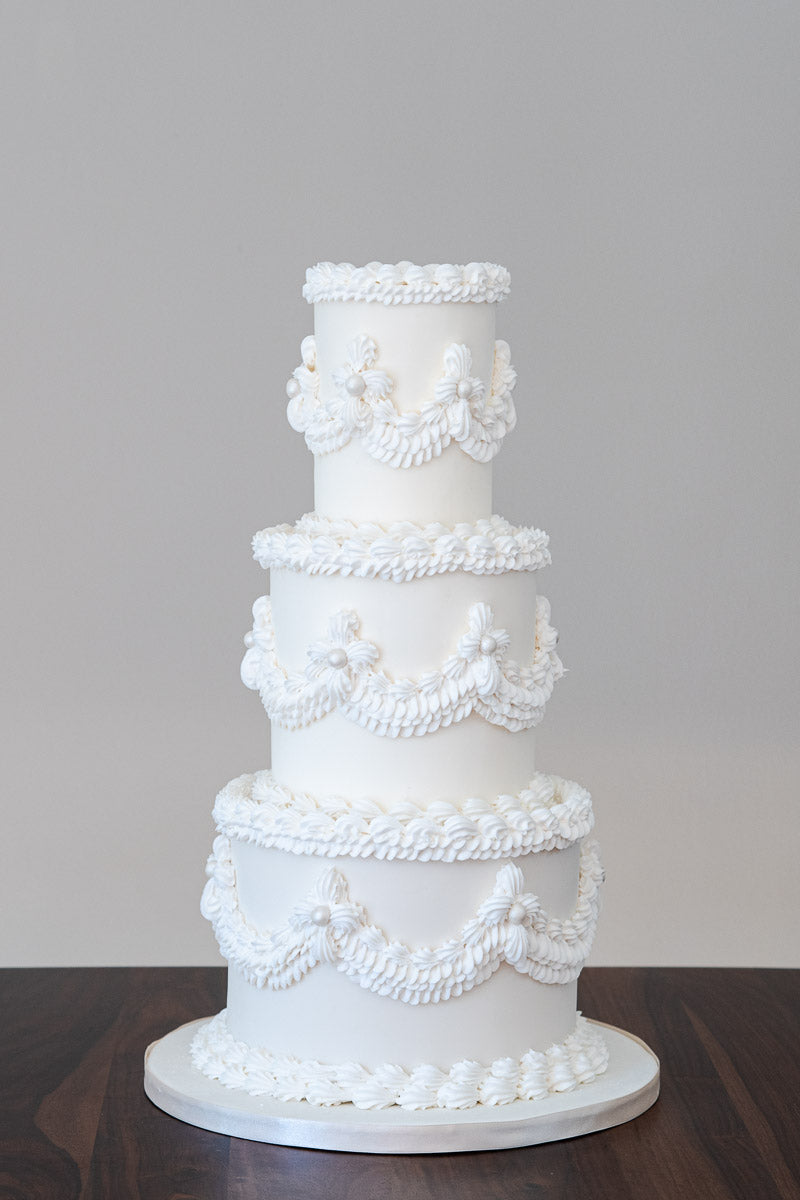 Retro Bridgerton inspired wedding cake using Lambeth piping style, draped with royal iced swags, ruffles, shells and pearls..