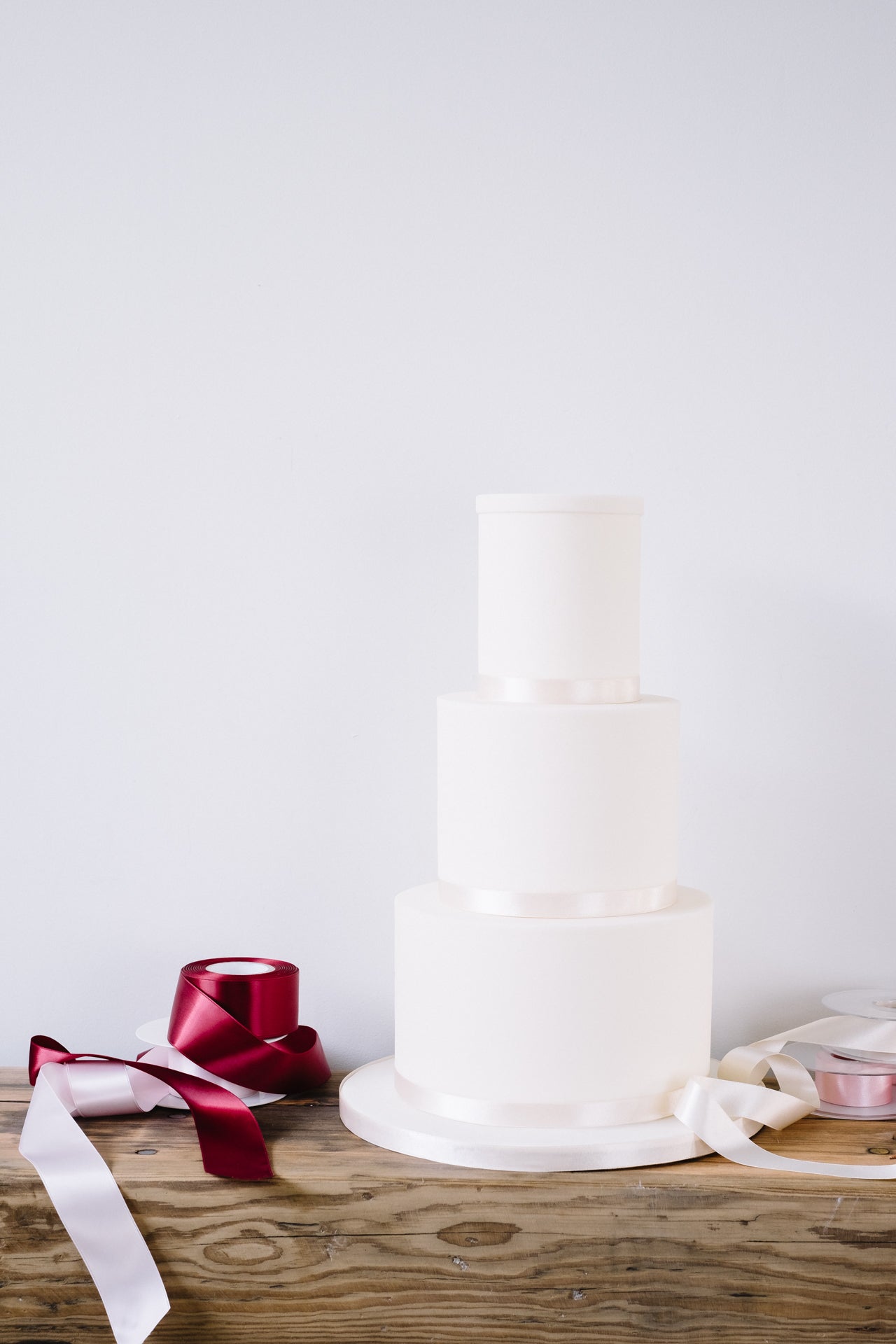 Our version of a naked wedding cake. Finished in smooth sugarpaste and neutral ribbon.
