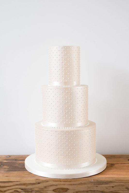 Simple and understated deep tiered modern wedding cake with sharp edges in a luxurious champagne colour with piped pearls by Saddleworth based Union Cakes