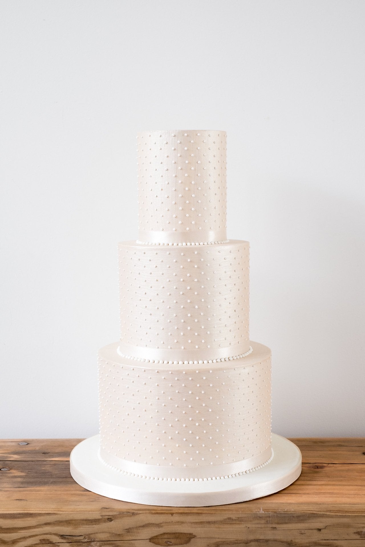 Simple and understated deep tiered modern wedding cake with sharp edges in a luxurious champagne colour with piped pearls by Saddleworth based Union Cakes