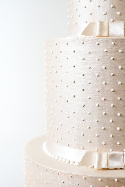 Simple deep tiered modern wedding cake in a luxurious champagne colour with piped pearls and satin ribbon.