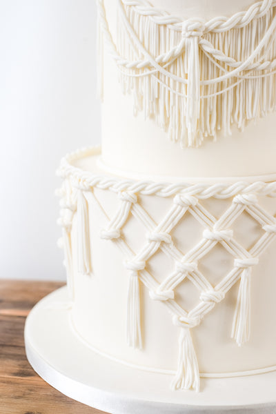 Detail of beautiful natural looking sugar macrame lace on a modern ivory wedding cake